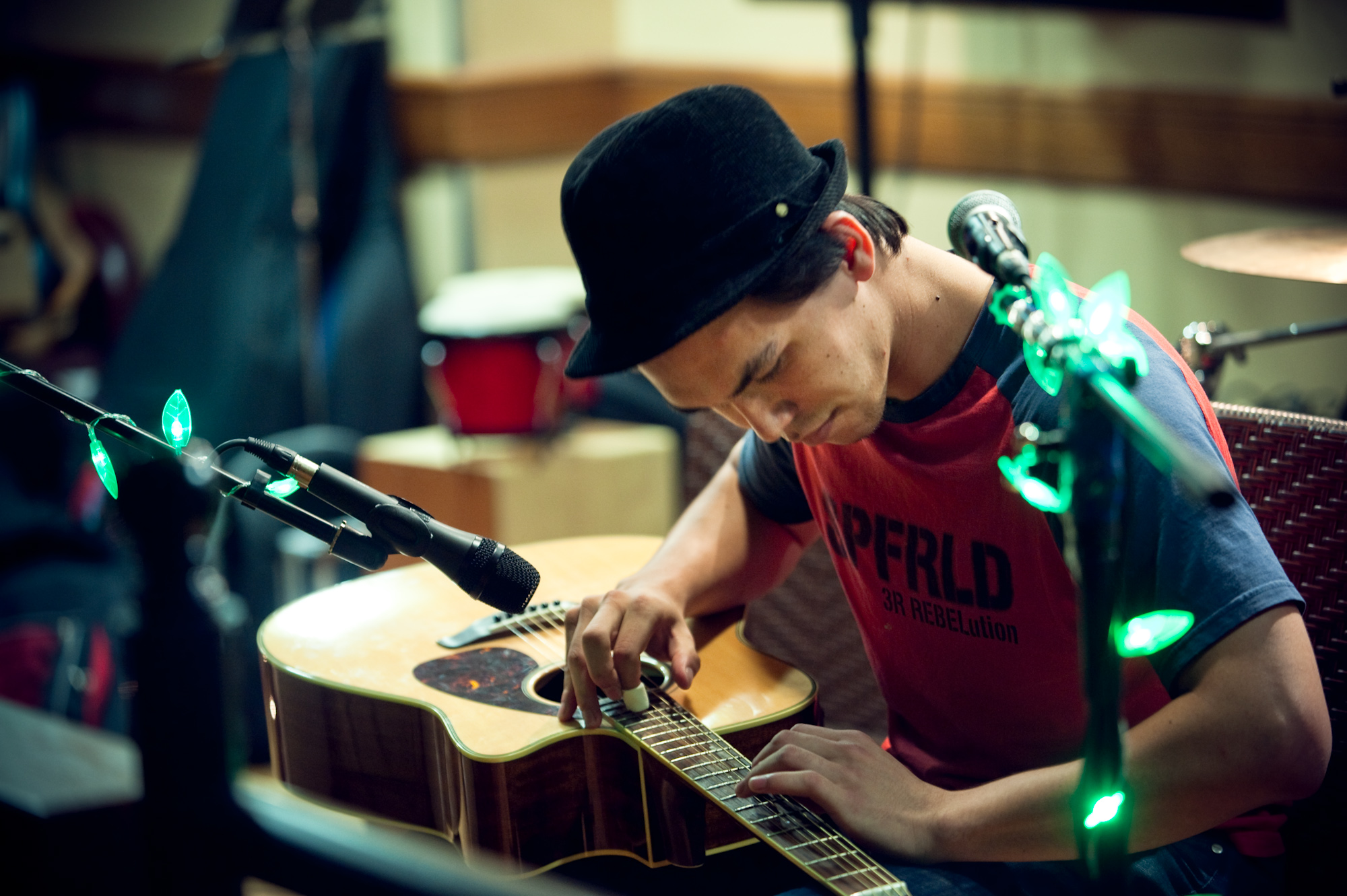 Guitarist playing an acoustic set beside a microphone and green stage lights