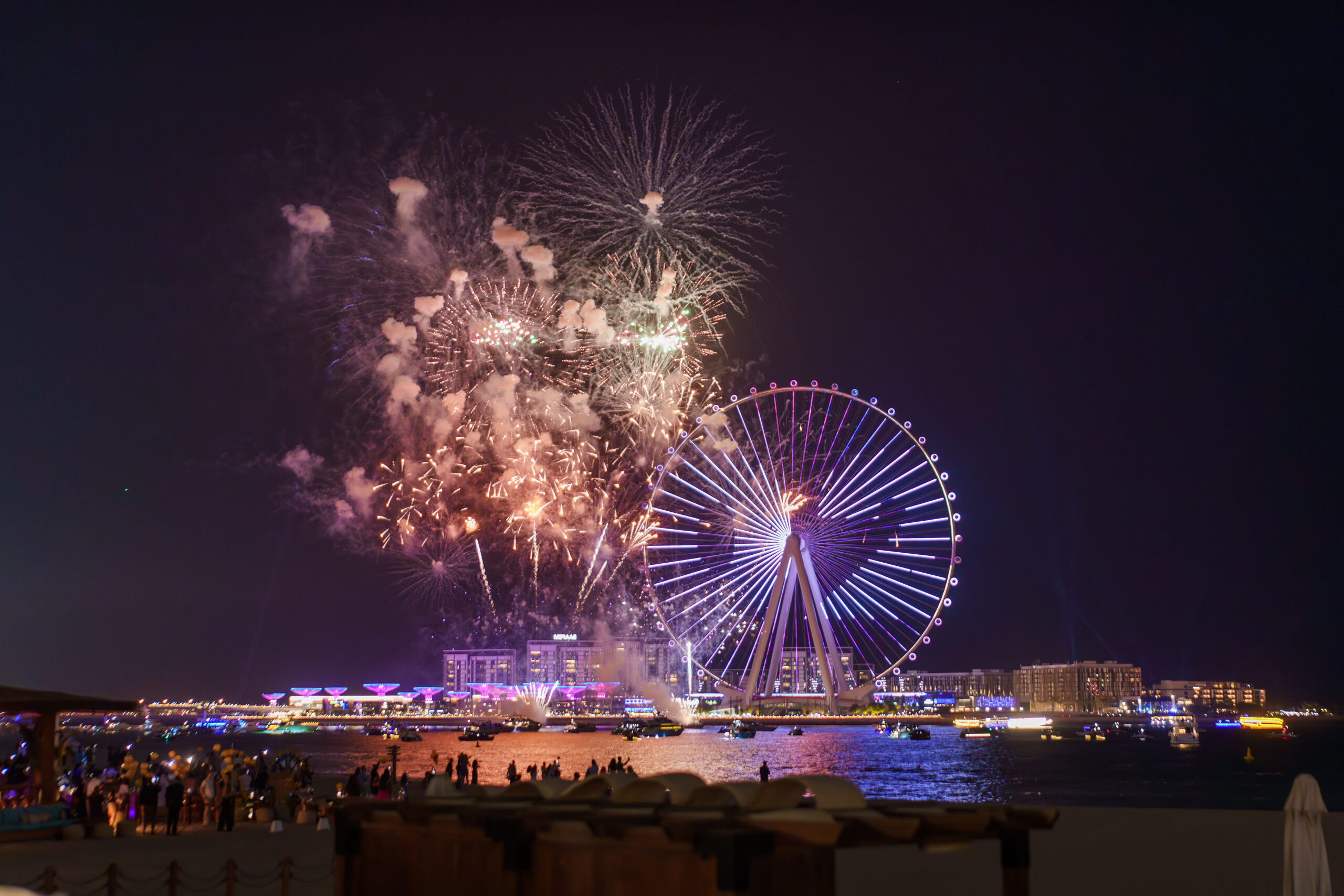 Fireworks over Bluewaters Island as a crowd watches from the beach in Dubai